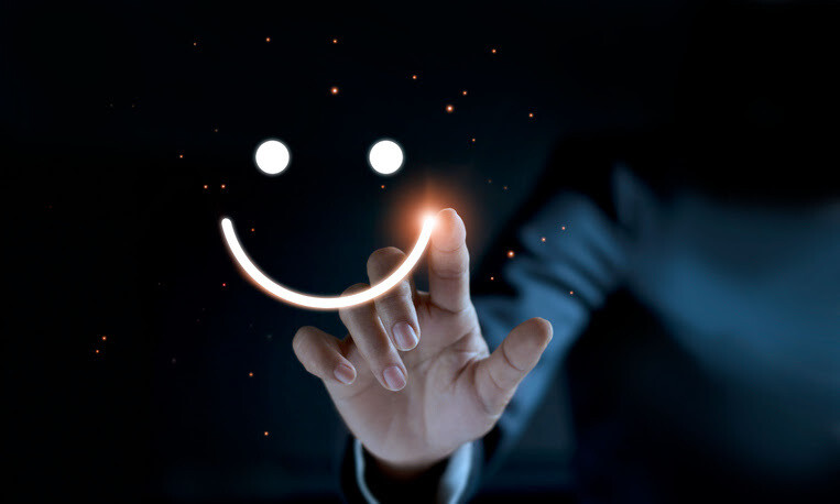 Hand drawing a glowing smiley face in the dark with sparkles around it.