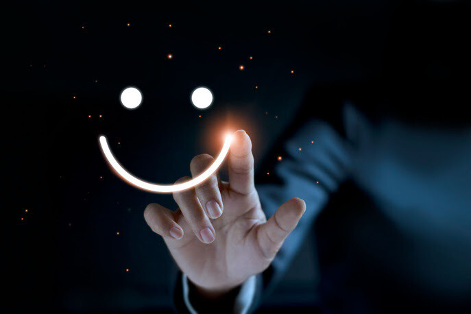 Hand drawing a glowing smiley face in the dark with sparkles around it.