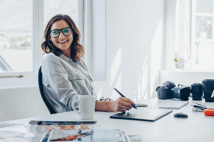 Smiling woman with glasses working on a digital tablet in a bright photography studio