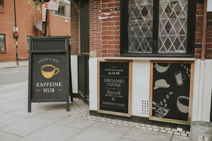 Exterior of a café with decorative signs and menu board displayed on the sidewalk