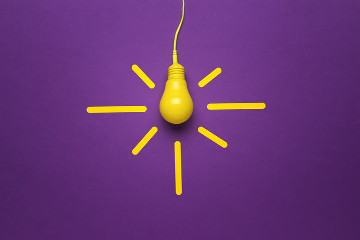 Bright yellow bulb with radiating lines on purple surface