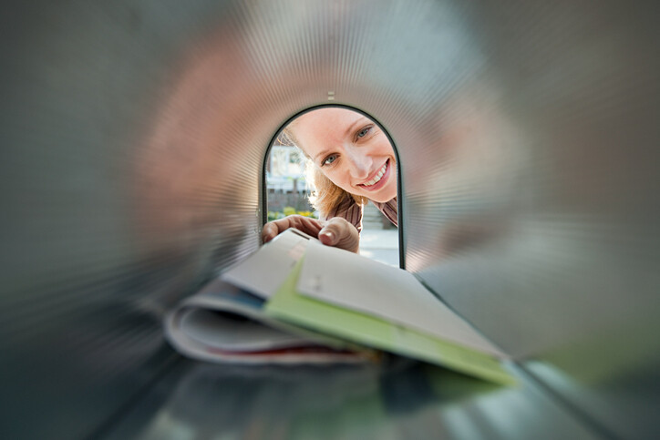 View from inside a mailbox as a woman reaches in to collect her mail.