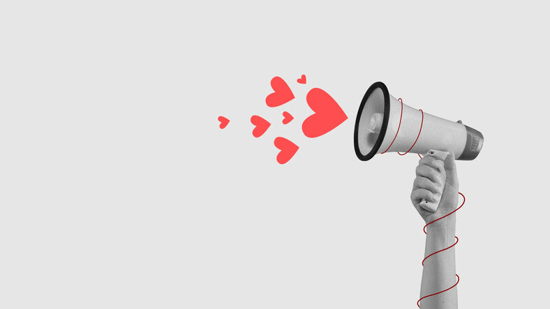 Hand holding a megaphone with red hearts coming out against a gray background.
