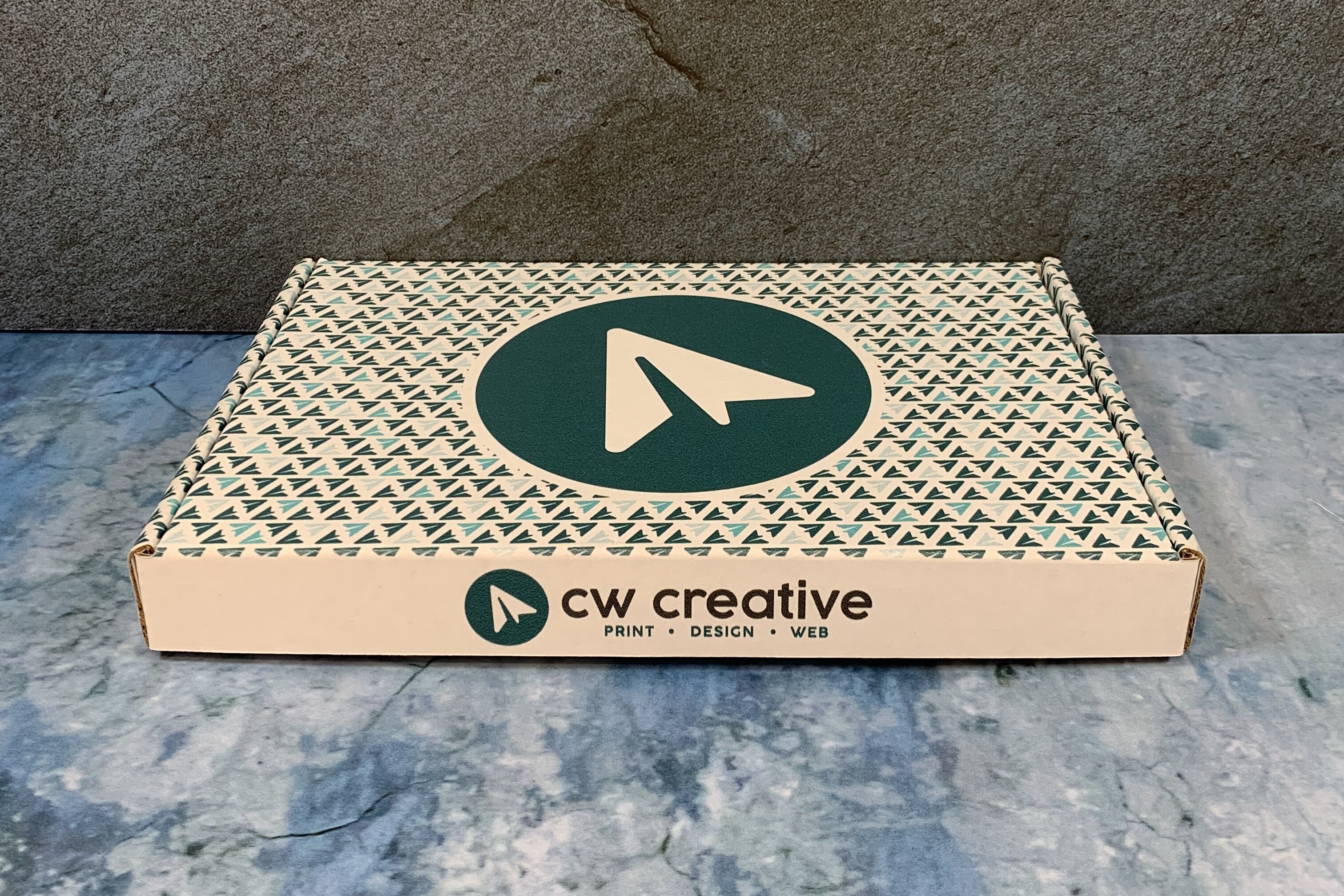 Branded box from CW Creative on a textured surface.