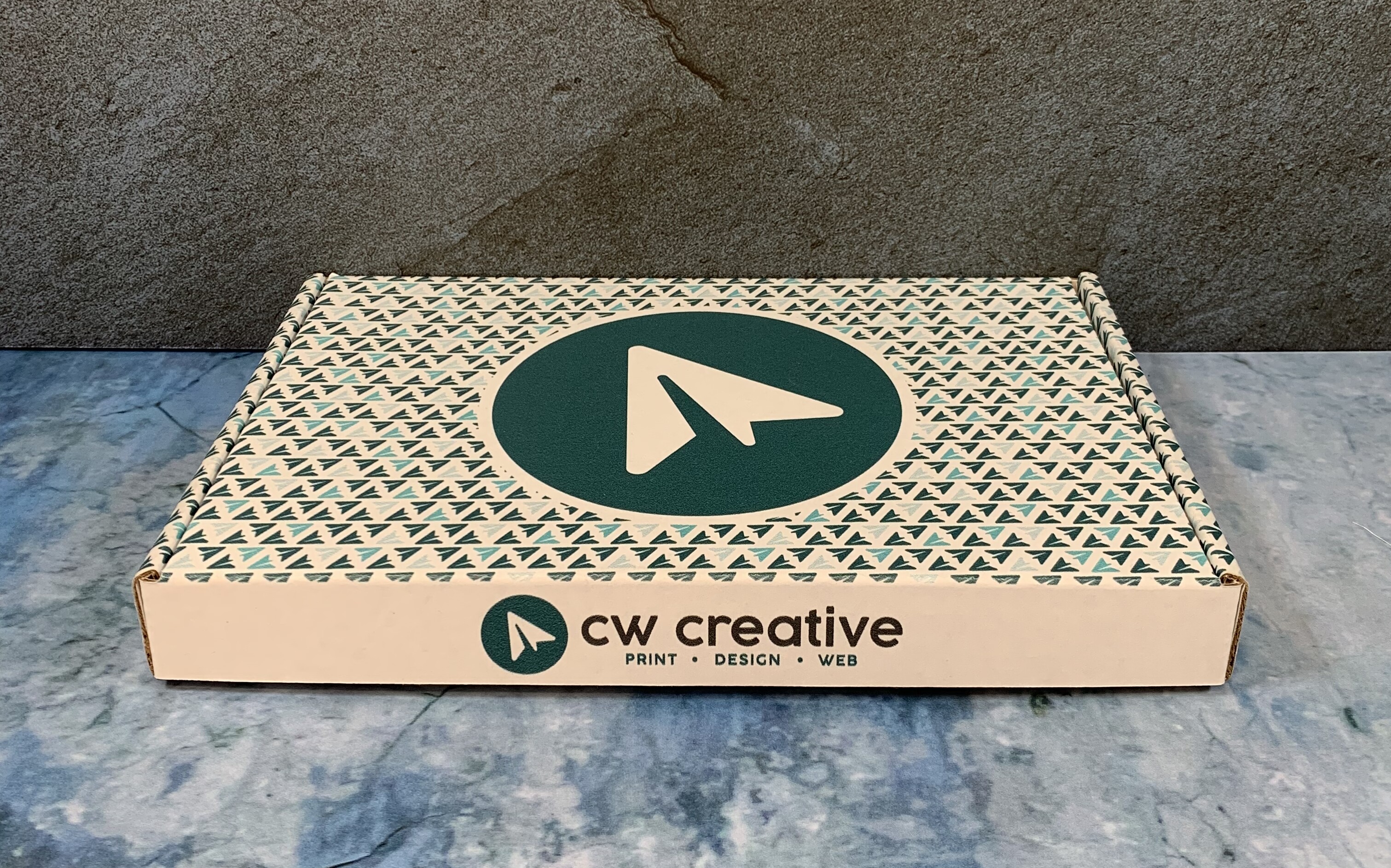 Branded box from CW Creative on a textured surface.