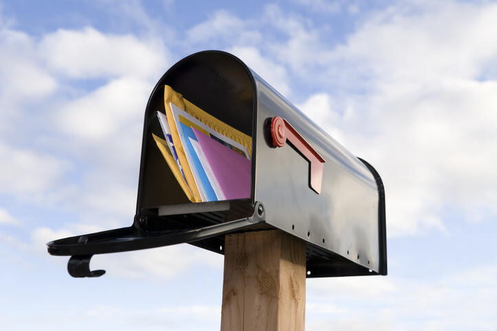 Side view of an overstuffed mailbox with colorful envelopes.