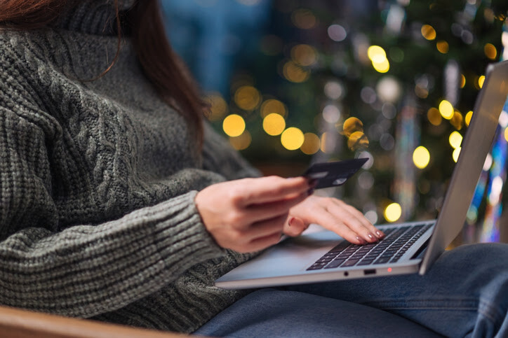 Close-up of hands holding a credit card and typing on a laptop during holiday shopping.