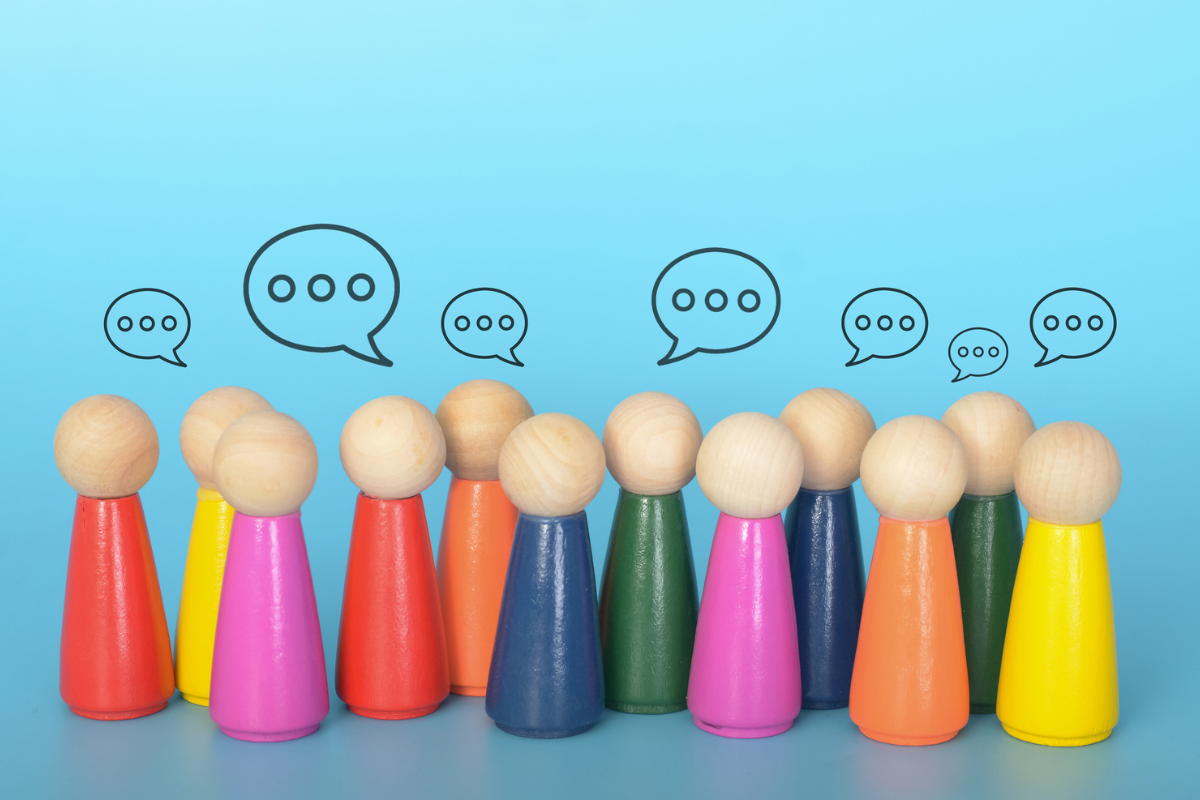 Colorful wooden peg people with speech bubbles above them, representing communication