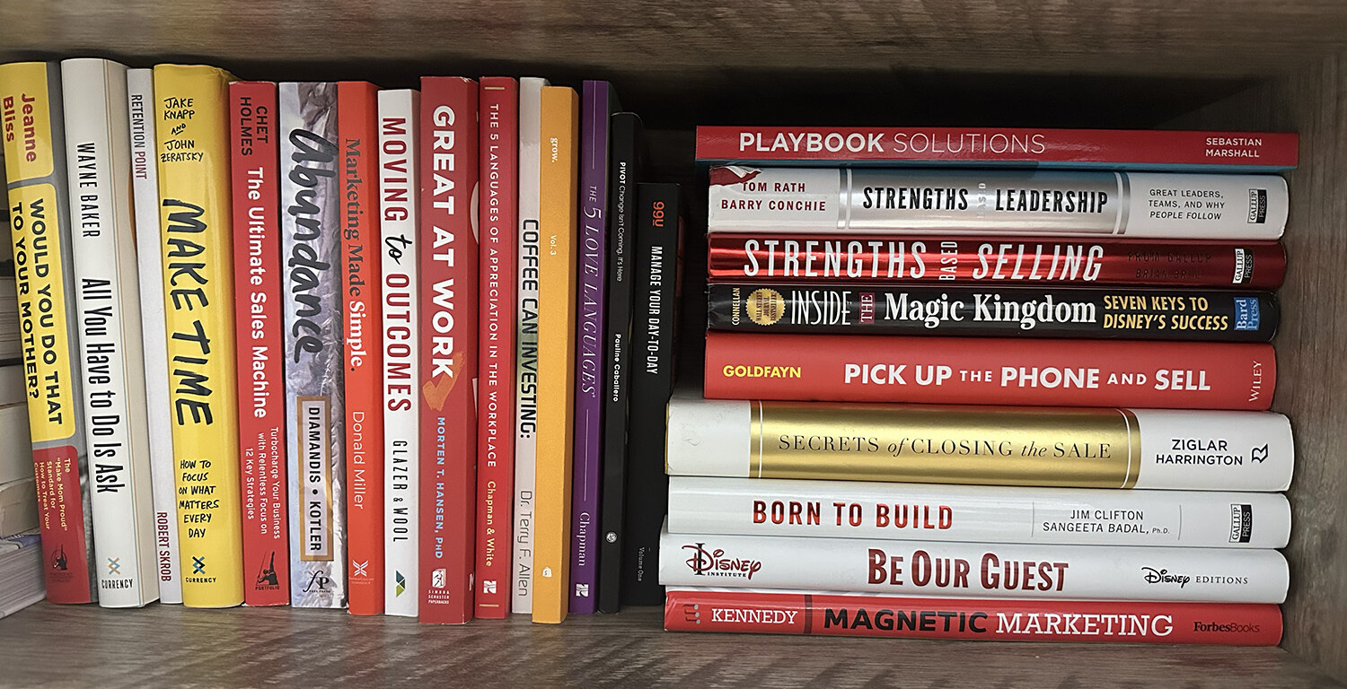 Organized bookshelf with titles on sales, leadership, and productivity.