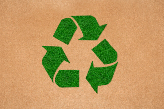 Green recycling symbol on brown cardboard background, representing sustainability and eco-friendly practices