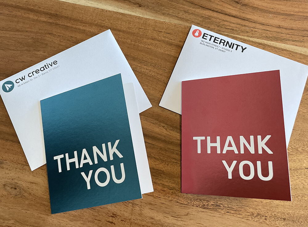 Thank you cards and envelopes from CW Creative and Eternity on a wooden surface.