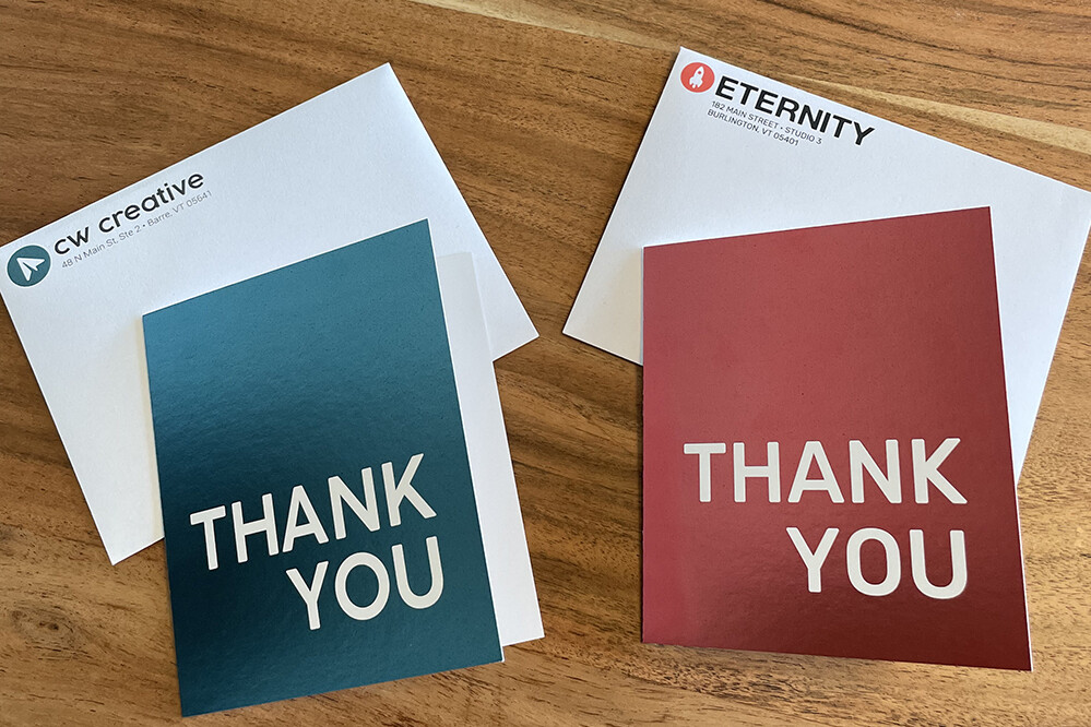 Thank you cards and envelopes from CW Creative and Eternity on a wooden surface.