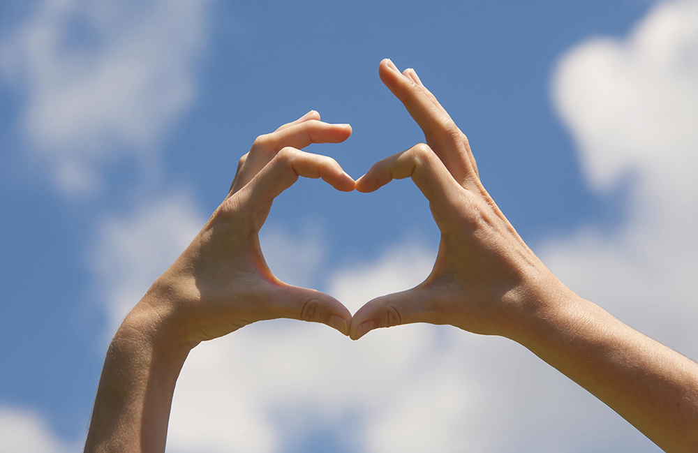 hands in shape of heart in the sky